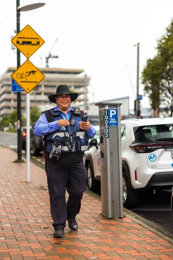 Auckland Transport parking officer wearing a high-visibility vest with a secure body-worn camera attachment and reflective elements for safety.